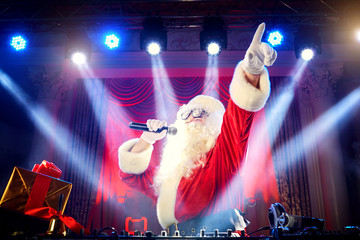 Dj  Santa Claus mixing at the party at Christmas, raised his han