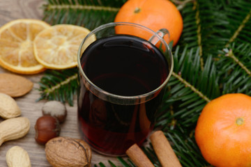 Glühwein mit Orange und Zimtstange auf Holz mit Tannen und Nüssen
