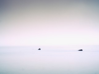Fototapeta premium Pink sunset at rocky coast of sea. Smooth water level and dreamy effect