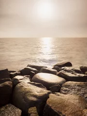 Fotobehang Big wet boulders in shore in smooth wavy sea. Stony coast defies to waves © rdonar