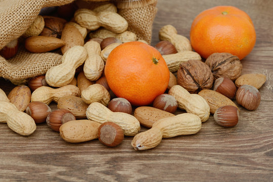 N&uuml;sse und Mandarinen auf Holz mit Jute Beutel