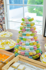 Colorful macarons on pyramid-shaped plastic stand at party