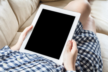 Woman using tablet computer sitting on a  sofa