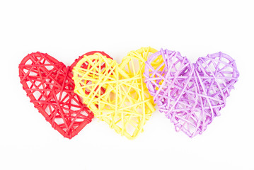 Three wicker hearts on woven wood in heart shape. Yellow, red, purple woven Valentines day/Christmas/ Mothers day/ anniversary decorations - hearts isolated, on white background.