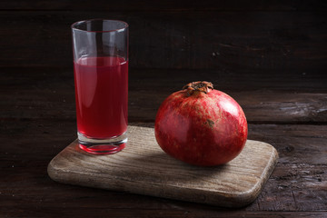 a pomegranate with pomegranate juice on a wooden board on a wooden background