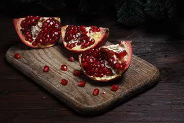 cut part of pomegranate on a wooden board on a wooden background on the background of trees. New Year's holiday. tree branch