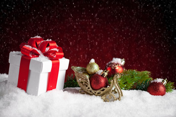 Christmas gift and baubles on red bokeh background