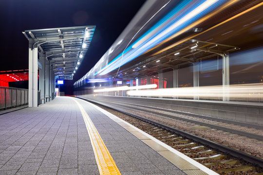 Modern railway train station at night. Bright colors and rapid blurred movement. Fast pace business abstract concept.