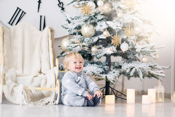 Beautiful little baby boy in pajamas with stars celebrates Christmas