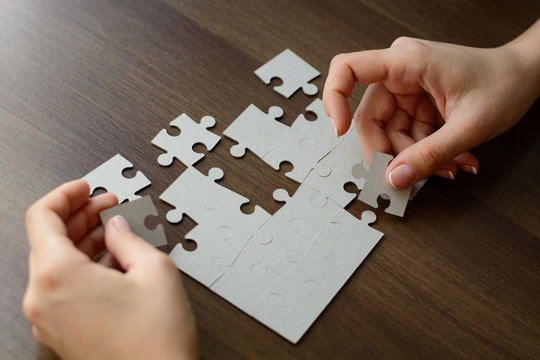 Image of businesswoman connecting elements of white puzzle