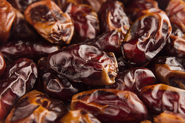 Date fruit closeup background. Heap of dried shiny brown red date fruit. Top view.