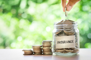 Hand putting Coins in glass jar for money saving insurance 