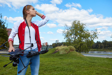 Brunette coed flying a drone in the outdoors .