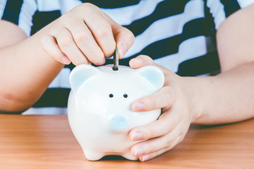 Woman hand putting coin into piggy bank
