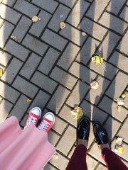 Two people standing on the ground - top view. Autumn leaves