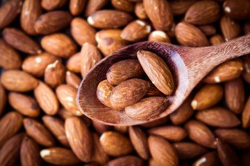 close up Peeled almonds nut in spoon on almond  background