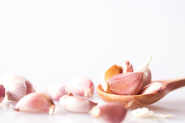 Close up garlic in a wooden spoon on white background