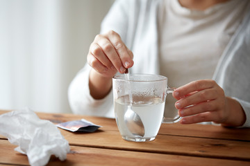 woman stirring medication in cup with spoon