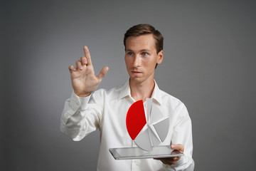 Man in white shirt working with pie chart on a tablet computer, application for budget planning or...