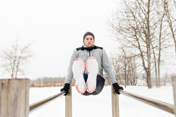 young man exercising on parallel bars in winter