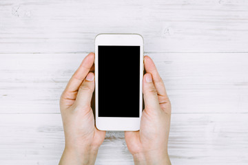 Women hand holding smartphone on wooden background