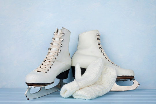 Vintage ice skates for figure skating and knitted mittens on turquoise background