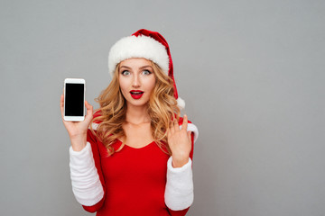 Surprised young woman in new year costume showing cell phone