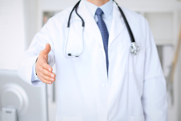 Male medicine doctor offering helping hand  for  handshake. Partnership and trust concept.