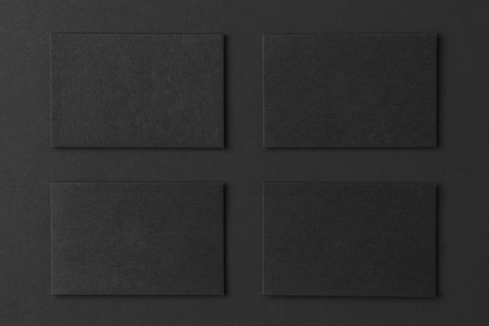 Mockup of black business cards arranged in rows at black paper