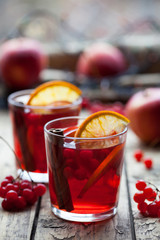 The concept of homemade mulled wine. Sangria or punch with orange, apple and berries in a glass on a wooden table. Creative decoration.