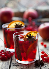 Winter warm drink. Christmas mulled red wine or sangria with cinnamon sticks, anise stars, oranges and berries in a pot on a rustic wooden table