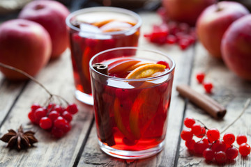 Homemade mulled wine or sangria with orange and apple slices, cranberries, cinnamon and anise on wooden table. Close up.