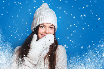 Love winter. Pretty young happy woman in winter clothes Woman surprise showing product .Beautiful girl with curly hair pointing to the side . Presenting your product