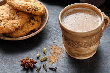 Obraz na płótnie Canvas Masala tea chai latte traditional hot Indian sweet milk spiced drink, teh tarik, ginger, cinammon sticks, fresh spices blend, anise organic infusion healthy wellness beverage in rustic clay cup