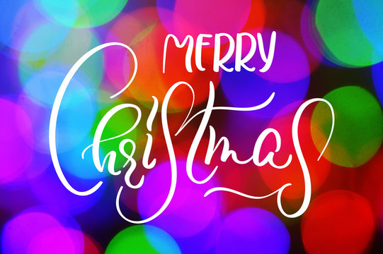 Colorful bokeh background with words Merry Christmas. Calligraphy lettering