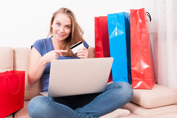 Woman sitting on couch holding laptop pointing card