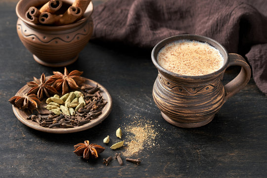 Masala pulled tea chai latte hot Indian sweet milk spiced drink, cinnamon stick, cloves, fresh spices and herbs blend, organic infusion healthy wellness beverage teatime ceremony in rustic clay cup