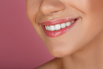 Beautiful smile with whitening teeth. Dental photo. Macro closeup of perfect female mouth, lipscare. Perfect pink lip makeup. Perfect clean skin, light fresh lip make-up. Pink background