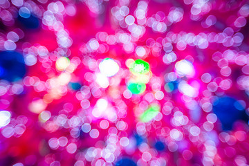 Pink background of bokeh defocused christmas lights from a christmas tree with lights and xmas balls.
