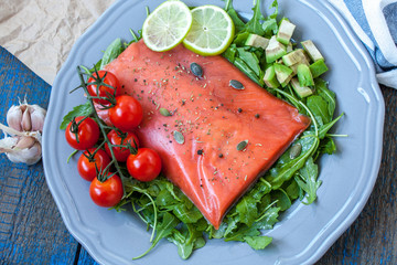 Salted salmon with herbs, tomatoes and salad on a wooden board. Love for a healthy raw food concept