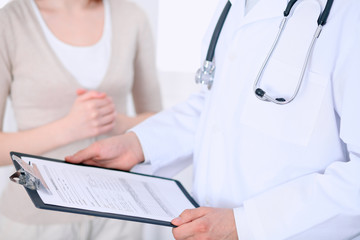 Close up of a male doctor holding an application form while consulting patient