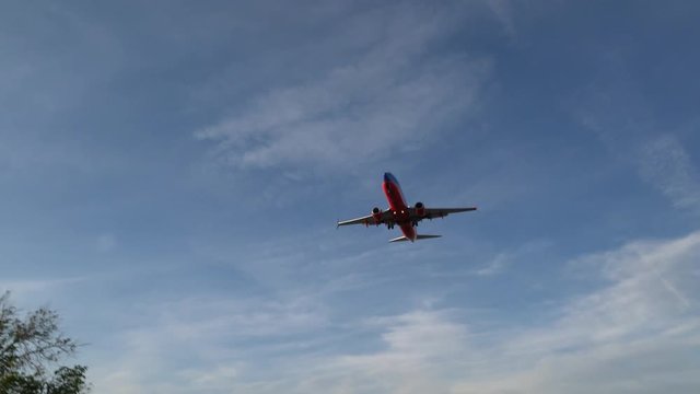 Low angle view of red airplane flying from airport after takeoff at the sunny summer day