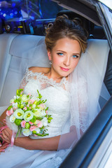 Beautiful, charming bride in  wedding dress sitting in limousine