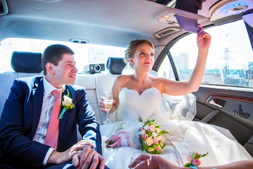 Happy newlyweds ride in wedding limousine