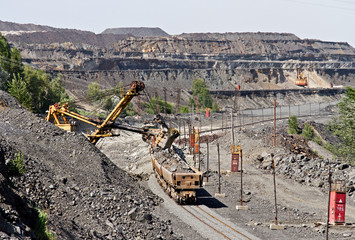 Excavator loading iron ore into goods wagon on the iron ore opencast mine