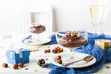 Chocolate pudding mousse with avocado, nuts and holiday decorations. Delicious Christmas themed dinner table.