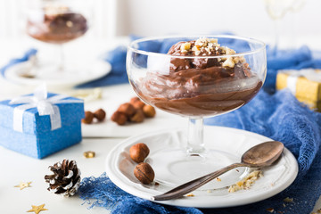 Chocolate pudding mousse with avocado, nuts and holiday decorations. Delicious Christmas themed dinner table.