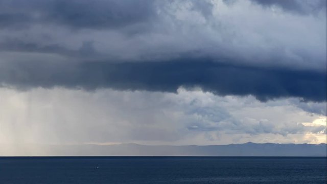 Stormy clouds and rough wind coming over calm blue sea time lapse