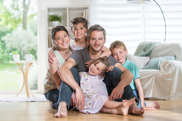 At home,  cheerful family sitting on floor in the living-room.