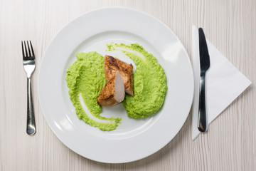 Detail of grilled chicken steak with mashed green peas up on a plate
